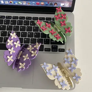 Three butterfly hair claws with flower details in green, purple and white on a laptop keyboard