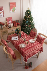 Detail of red and beige Christmas tablecloth featuring knitted reindeer and tree patterns