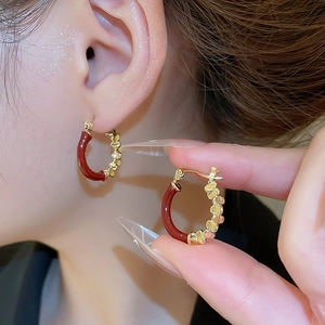 Gros plan de boucles d'oreilles créoles dorées avec émail rouge et motifs cœurs