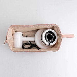 Pink travel organizer bag with mesh compartment storing hair dryer and diffuser nozzle