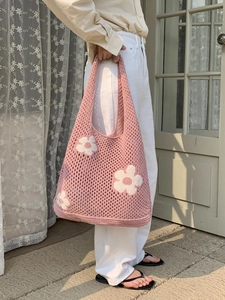 Nahaufnahme der rosa gestrickten Tragetasche mit weißen Blumenmustern und Hohlmaschenstruktur