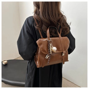 Détail du sac à dos vintage en similicuir marron avec breloque de baseball et boucle en métal