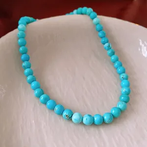Collier de perles turquoise vintage avec veines naturelles présenté sur une assiette blanche