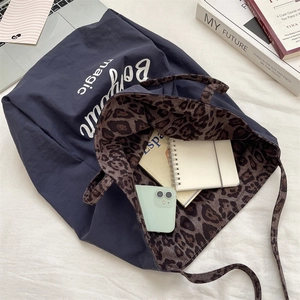 Detail view of spacious dark blue tote interior with leopard print lining and essentials