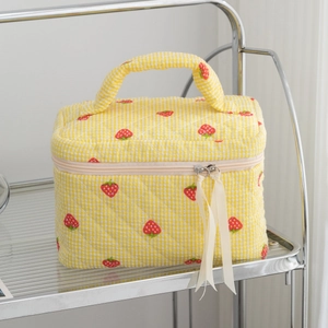 Detailed view of quilted makeup bag with yellow gingham and red strawberry prints