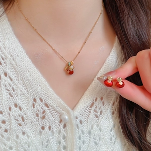 Detail of gold-plated lucky bag jewelry set with red zircon stones on a model