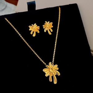Detail shot of gold-plated palm tree jewelry set on black velvet display