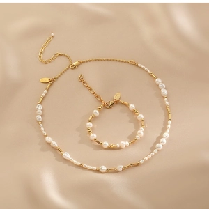 Elegant gold chain and baroque pearl necklace and bracelet set on champagne silk fabric