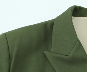 Dettaglio del blazer verde scuro con risvolto e trama del tessuto in twill di qualità