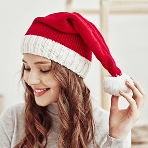 Close-up of red and white knit Christmas hat with soft pom-pom on female model