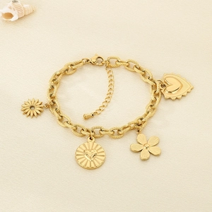Detail of golden charm bracelet with heart, flower pendants on beige background