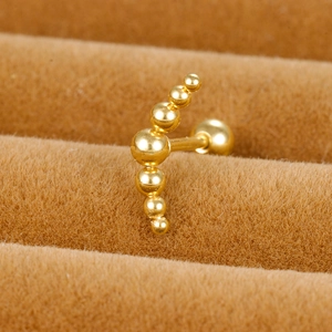 Close-up of golden curved seven-bead cartilage stud earring with a secure screw ball back