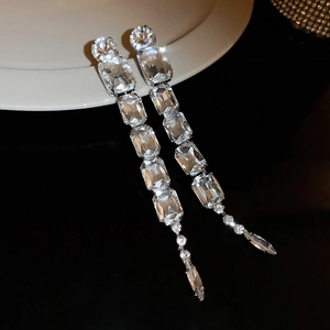 Detailed view of silver luxury tassel earrings with sparkling crystals on a white plate