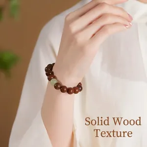 Minimalist sandalwood bead bracelet with green jade accent worn on a model's wrist