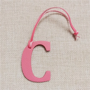 Close-up of pink leather letter C bag charm featuring detailed lychee grain texture