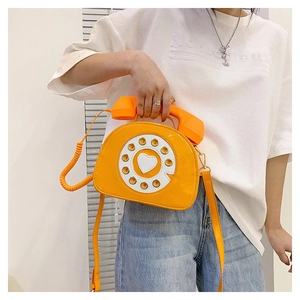 Detail of creative orange rotary phone cross-body bag with receiver handle and dial