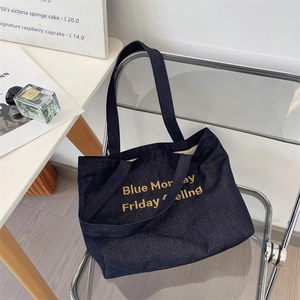 Dettaglio del ricamo dorato su borsa tote in denim blu scuro per moda quotidiana