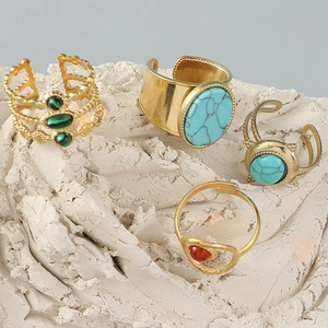 Macro shot of gold plated open rings with turquoise and malachite on stone texture