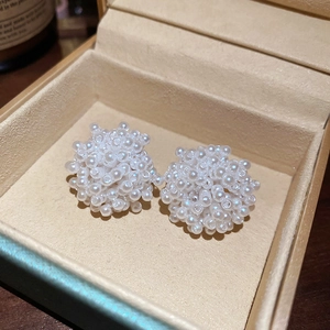 Vue macro de boucles d'oreilles fleurs en perles sur un écrin à bijoux en velours beige