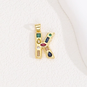 Close-up of golden letter K pendant with multi-colored cubic zirconia stones