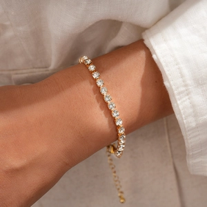 Detaillierte Nahaufnahme eines goldenen Tennisarmbands mit Kristallen am Handgelenk