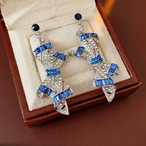 Close-up of vintage bow earrings with blue sapphires in a brown leather jewelry box