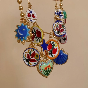 Macro shot of colorful enamel charms featuring sun and moon icons on a gold chain necklace