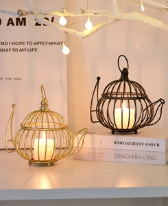 Detail of birdcage teapot metal candle holder in gold and black on white books