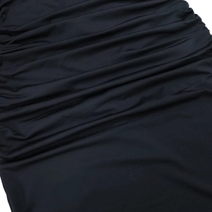 Macro shot of black ruched elastic fabric texture on a slim-fit evening maxi dress