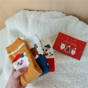 Gros plan de chaussettes de Noël épaisses en polaire corail avec motifs de renne et Père Noël