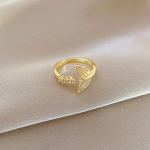 Detailed close-up of golden mermaid tail ring with zircon inlay on champagne silk