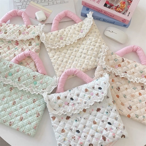 Flat lay of quilted laptop sleeves with floral and cartoon prints on a white desk