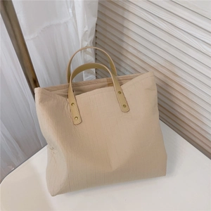 Close-up of beige cotton tote bag with vertical stripes and leather handle rivets