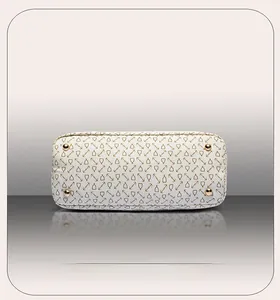 Detail of light beige tote bag bottom with gold studs and geometric chain pattern