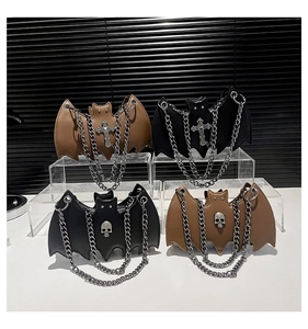 Close-up of gothic bat-shaped crossbody bags with metal chains and skull ornaments