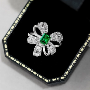 Macro detail of S925 silver bow ring featuring a green emerald-cut center zircon