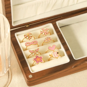 Detail view of 8-piece gold-plated flower heart enamel rings in wooden jewelry box