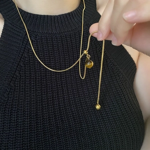 Sautoir en acier titane avec chaîne serpent dorée et pendentif sphérique en oeil de tigre