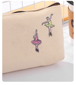 Detalle de bonitos pines de esmalte de bailarinas de ballet en un bolso de lona beige