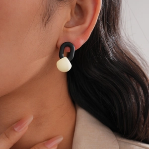 Modern minimalist black U-link and cream drop geometric earrings worn by model