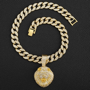 Gros plan du pendentif tête de lion doré serti de diamants sur une grosse chaîne cubaine