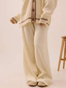 Detail showing the creamy beige knit fabric texture and relaxed fit of the wide-leg pants