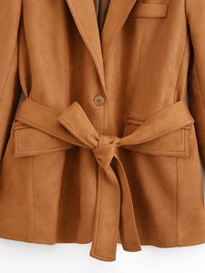 Dettaglio di un blazer in camoscio caramello con cintura abbinata e tasche
