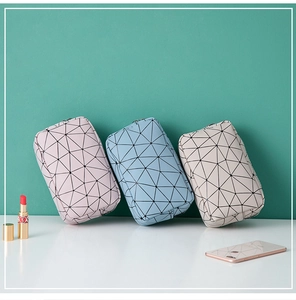 Three mini cosmetic bags in pink blue and beige with triangle patterns and zipper closure