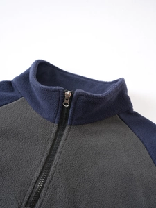 Close-up of tactical fleece jacket featuring standing collar and two-tone zipper detail