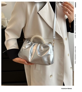Detail of silver pleated cloud bag featuring premium pearl handle and leather strap