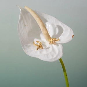 Makrodetail von goldfarbenem Bienenschmuck mit Zirkonia-Inlay auf Blumenhintergrund