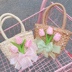 Close-up of woven straw bags with pink tulips and organza bows in a pink cart