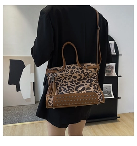 Detail of leopard print canvas bag with brown leather tassels and rivet decorations