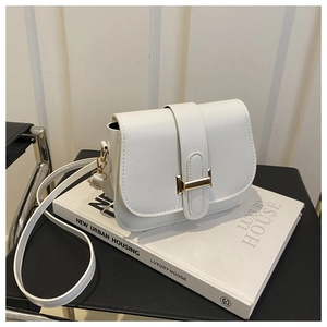 Close-up of white leather saddle bag featuring a polished gold H-shaped metal clasp